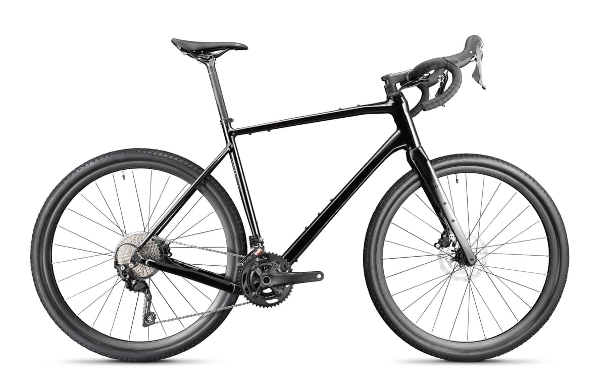 Black gravel bike with drop handlebars and knobby tires isolated on white background