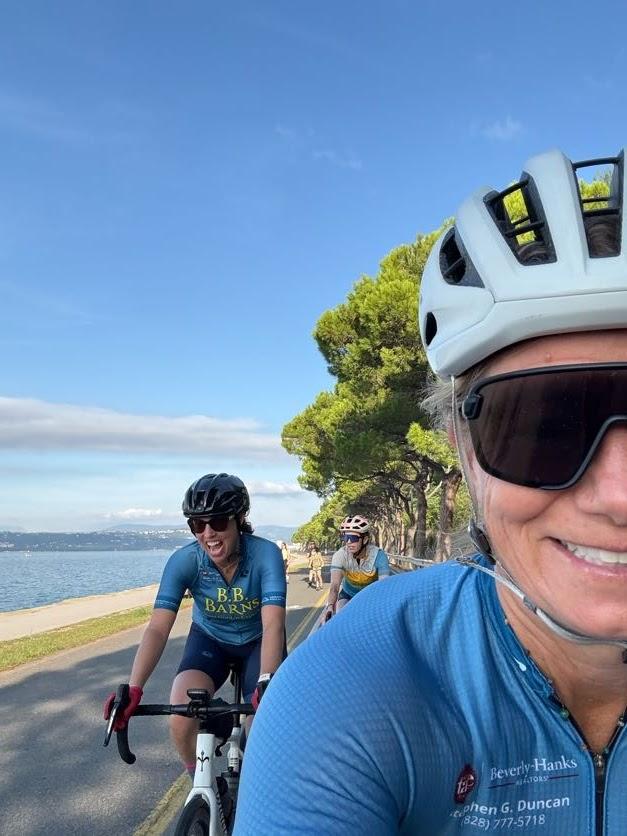 Cyclists riding road bikes along a sunny coastal path next to the water