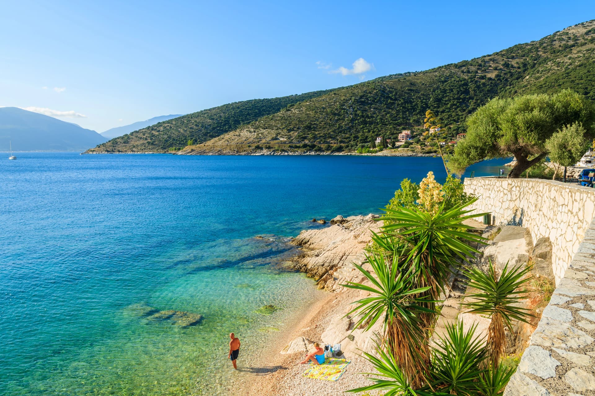 Unidentified couple of people relaxing on beach on coast of Kefalonia island in Agia Efimia, Greece